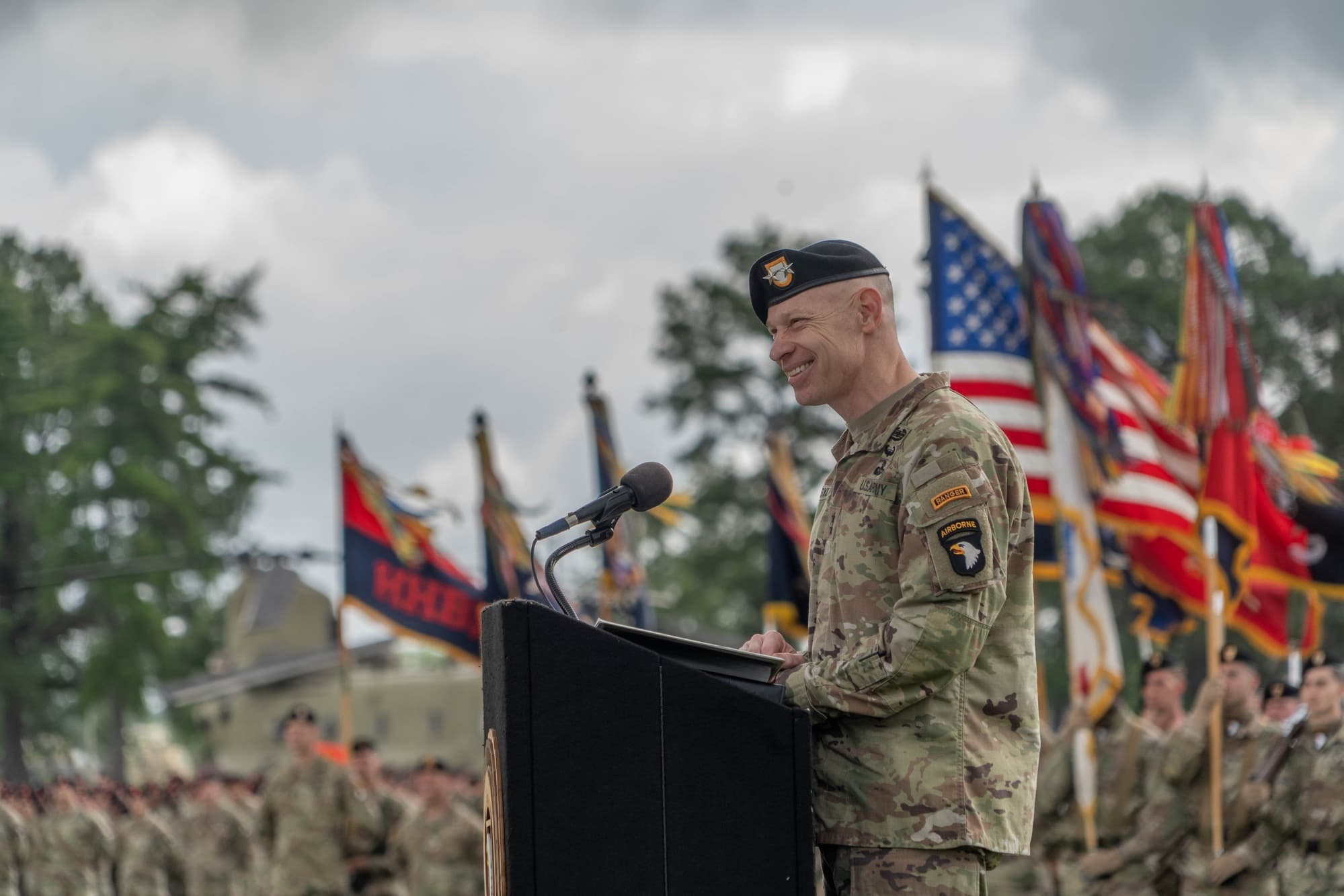 El mayor general Brett Sylvia, con uniforme del Ejército y boina negra, habla desde un podio durante una ceremonia de cambio de mando de la 101.ª División Aerotransportada en Fort Campbell en mayo de 2025.