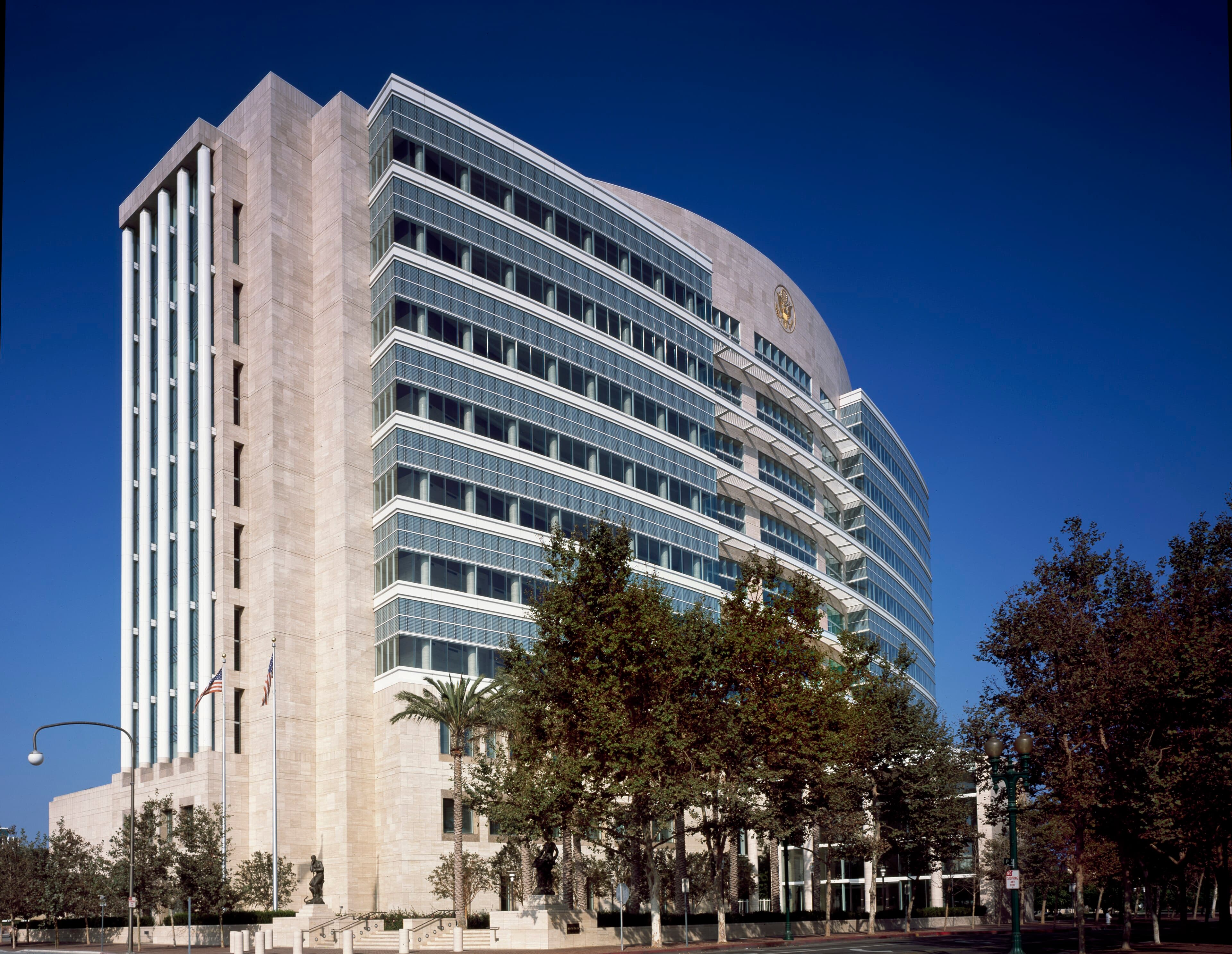 Exterior of the Ronald Reagan Federal Courthouse in Santa Ana, California, with a curved glass facade and blue sky.