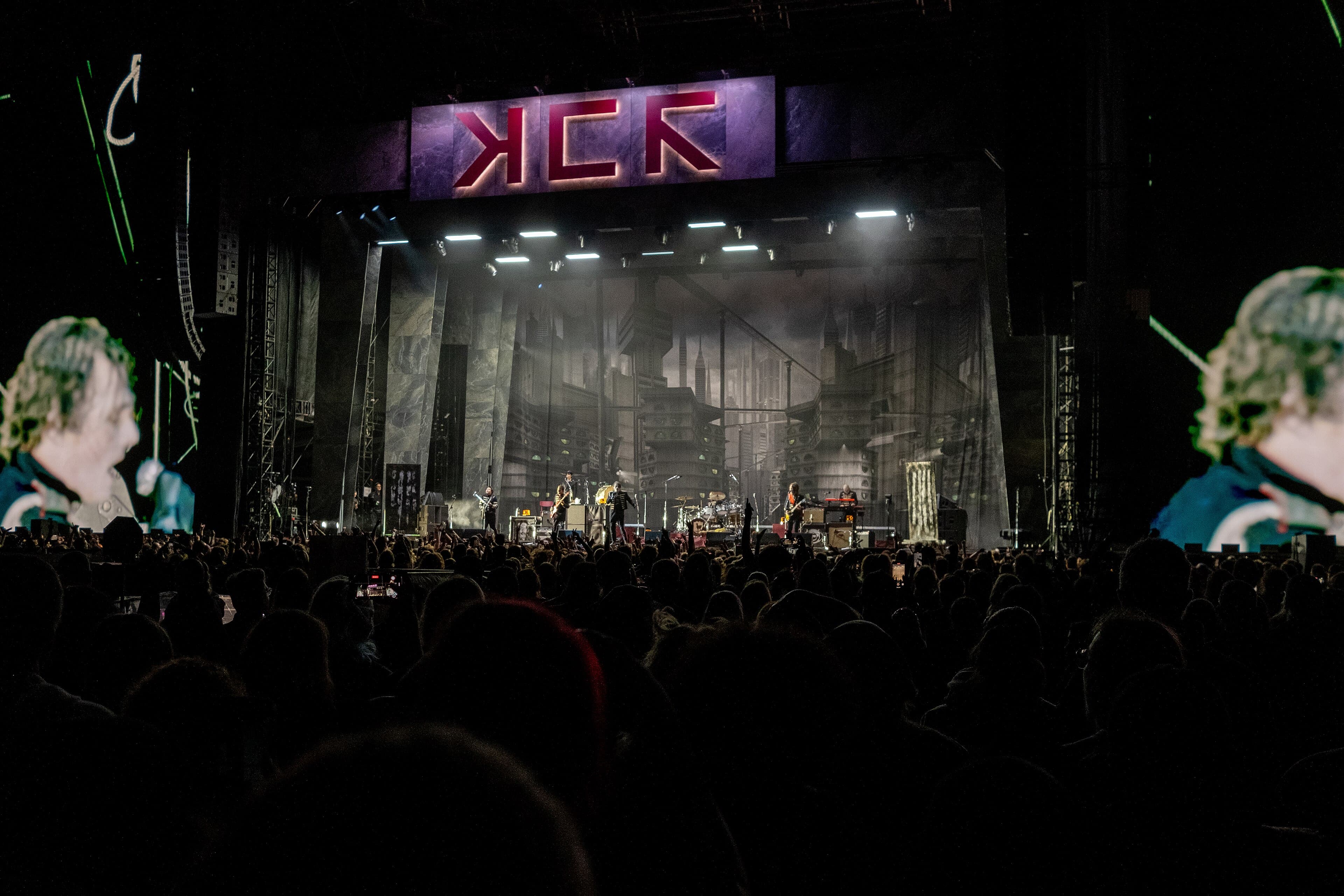 My Chemical Romance perform on a large concert stage at Fenway Park, with an audience in the foreground.