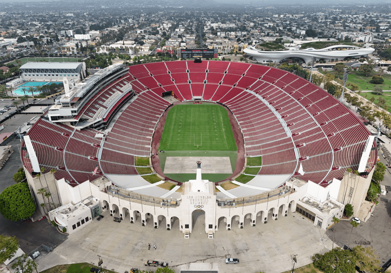 An aerial view of the Los Angeles Memorial Coliseum, its red seating and playing field.