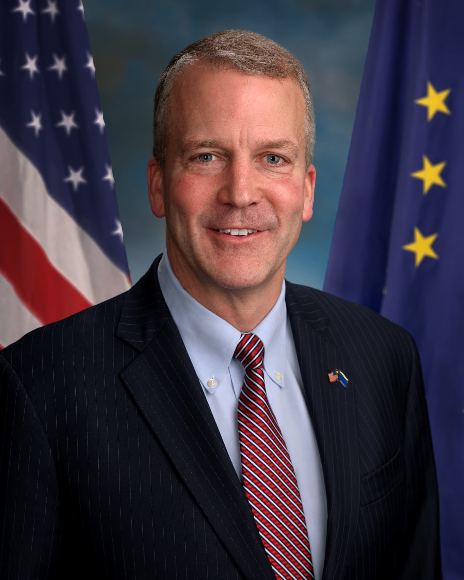 U.S. Senator Dan Sullivan in his official 2015 portrait, with United States and Alaska flags behind him.