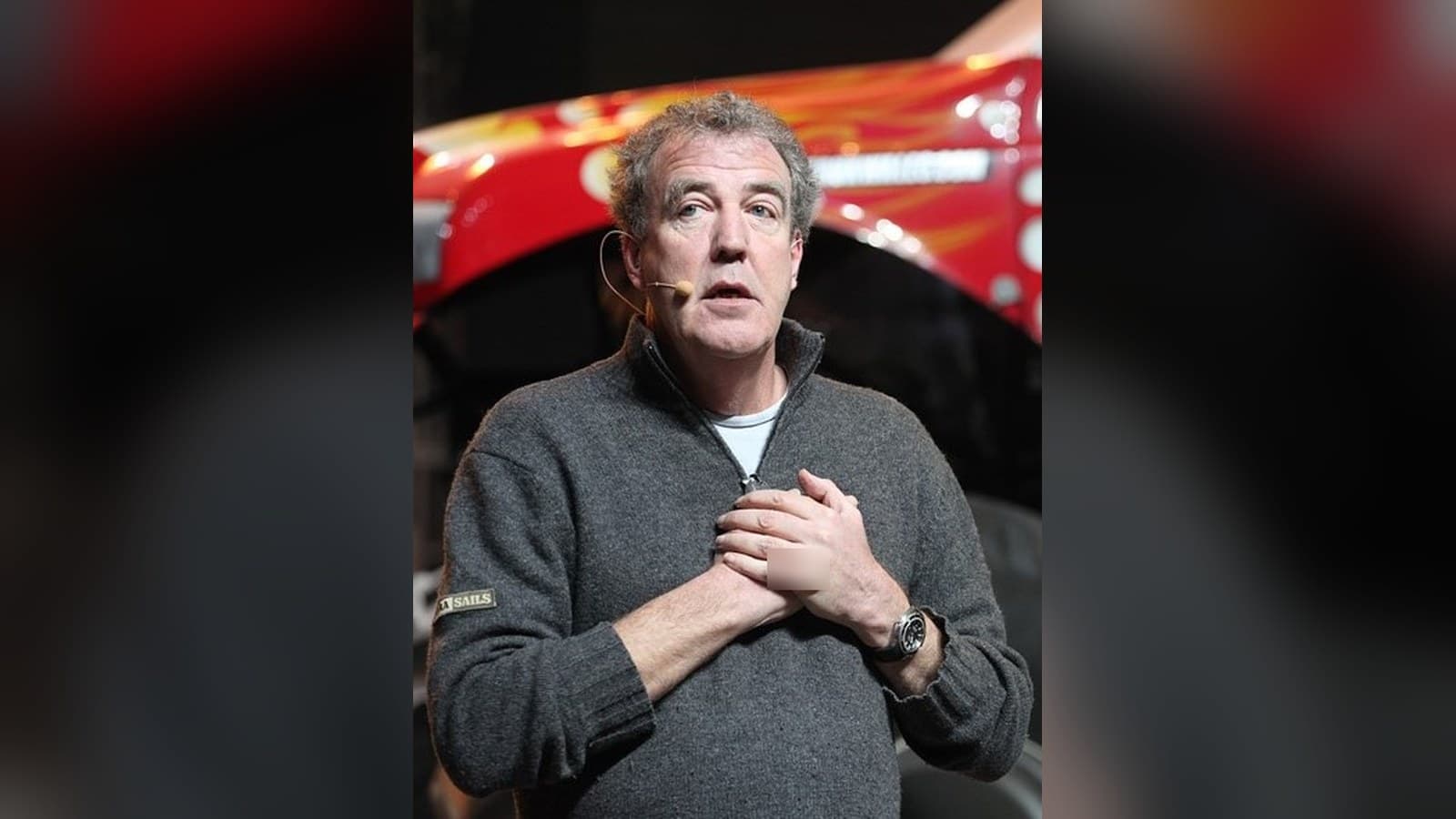 Jeremy Clarkson speaking on stage with a headset microphone.