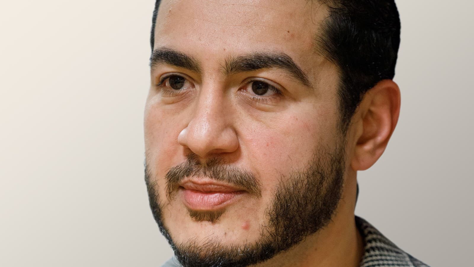 Close-up of Abdul El-Sayed, a bearded man with short dark hair, looking off to the side against a plain light background.