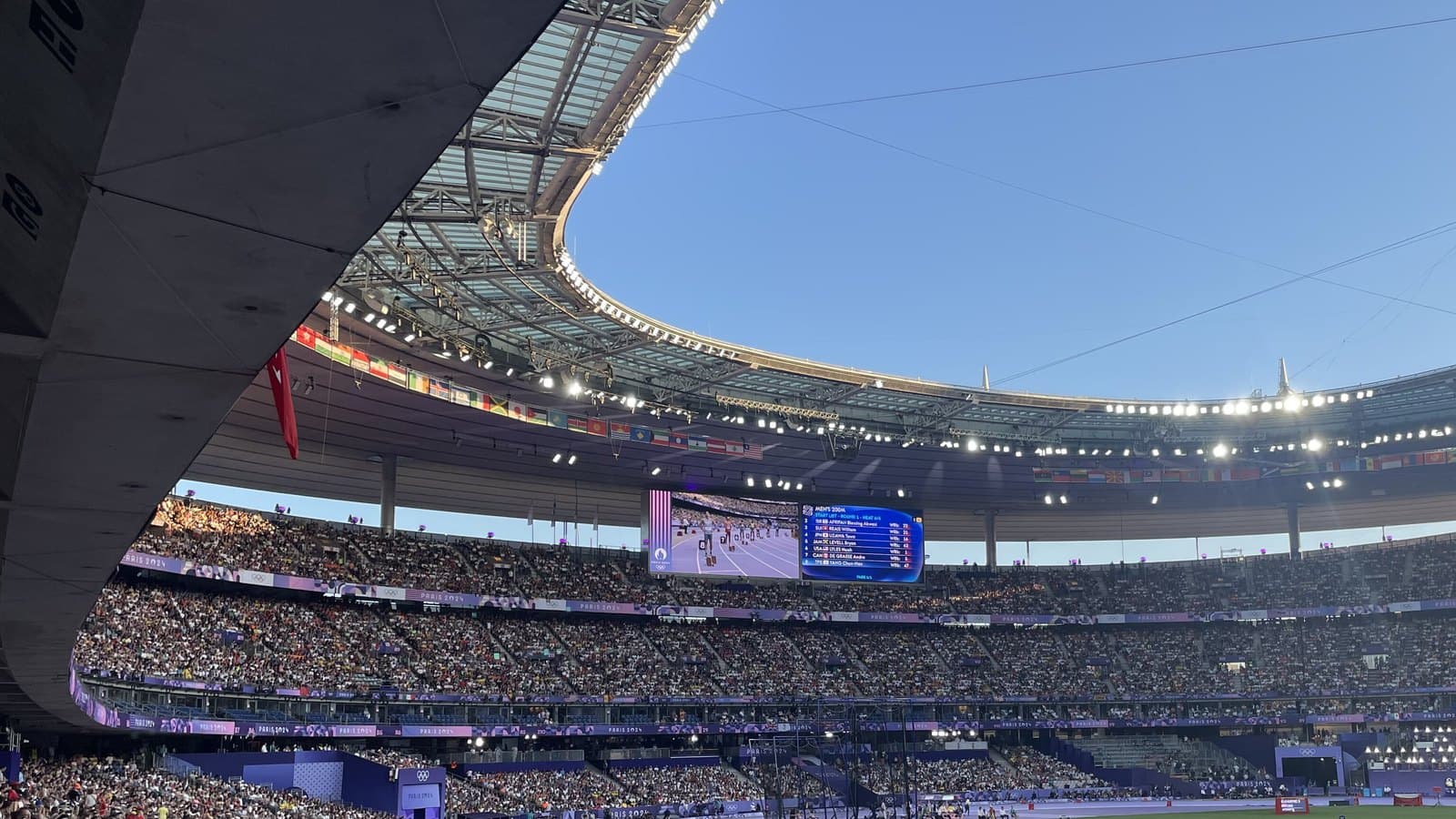 Crowd and roof of Stade de France on a sunny evening.