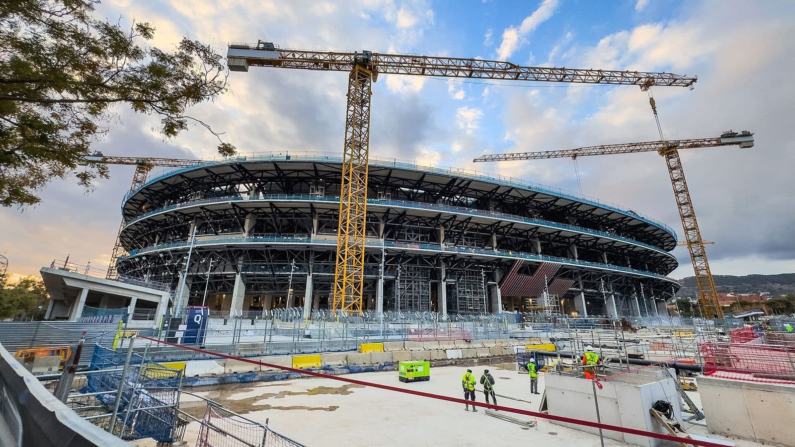 Camp Nou under reconstruction with yellow tower cranes and workers in hi-vis, Dec. 2025.