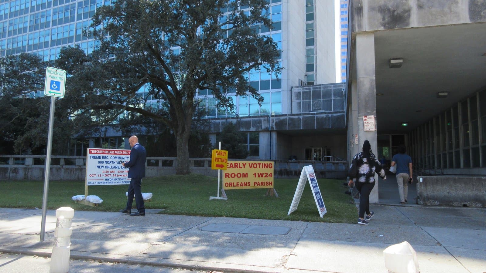 Letreros de votación anticipada en el césped frente al Ayuntamiento de Nueva Orleans, mientras los votantes caminan hacia la entrada, el 28 de octubre de 2024.