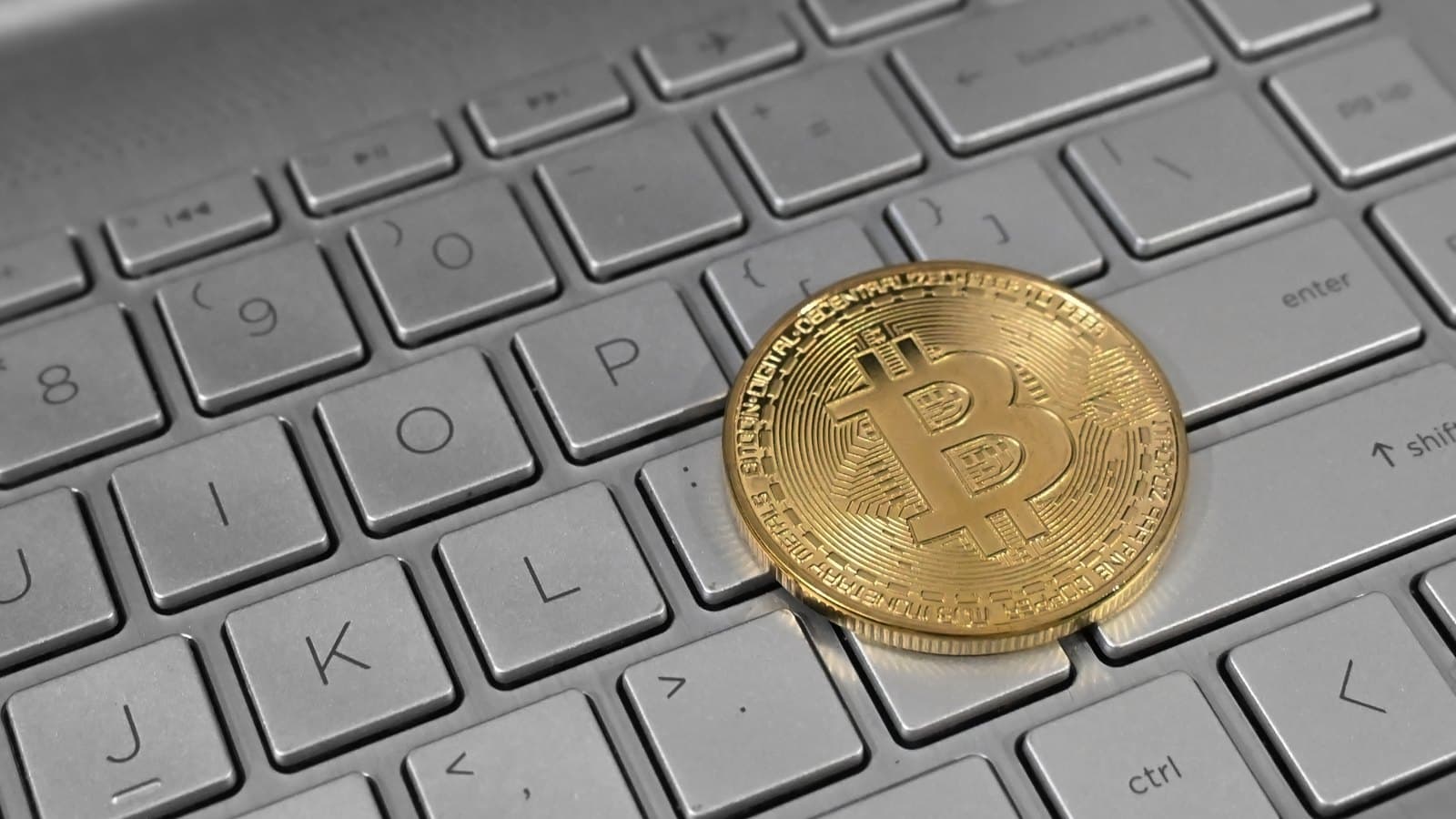 Una ficha de bitcoin sobre el teclado de una computadora portátil.