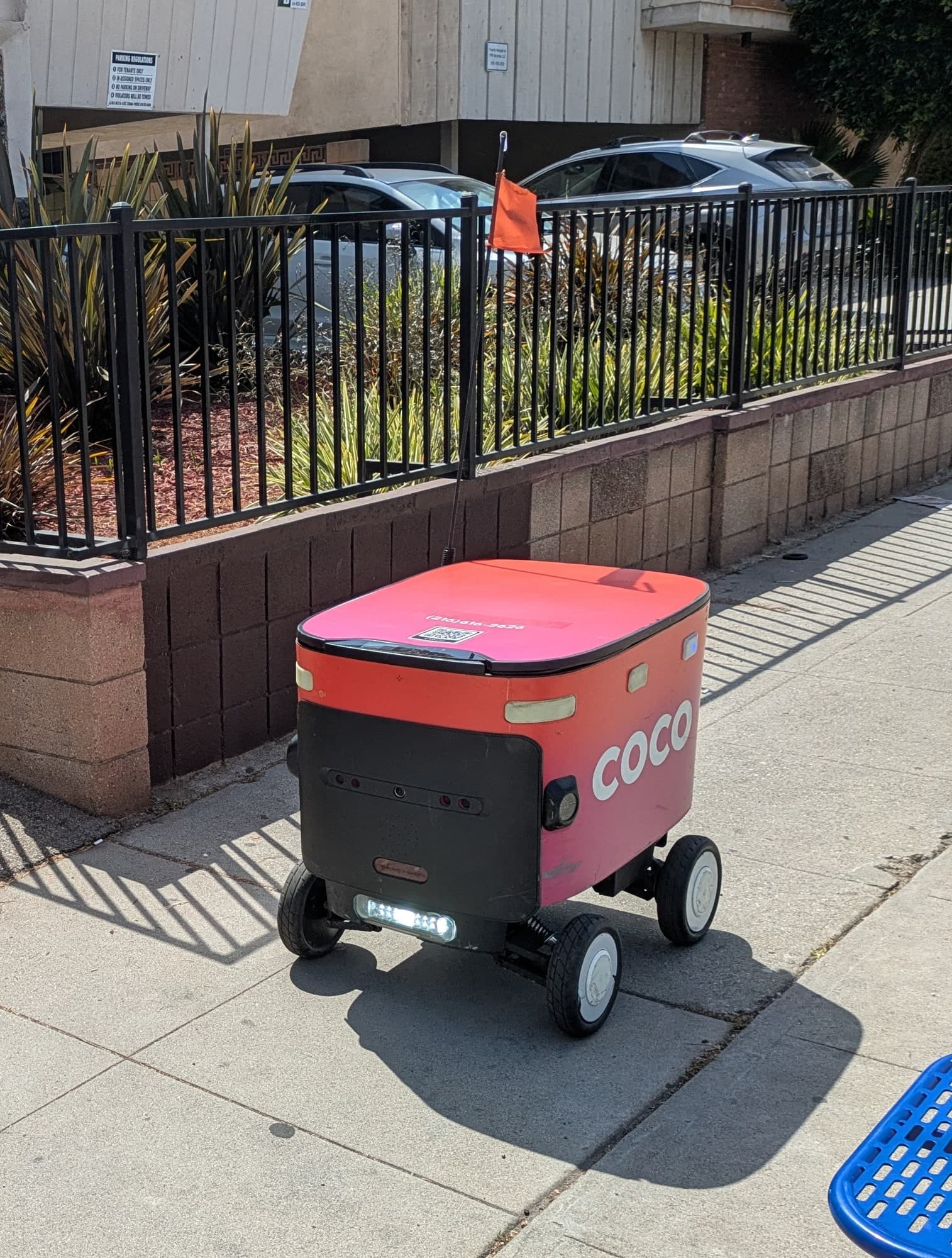 A pink Coco delivery robot on a sidewalk in Los Angeles in May 2025.