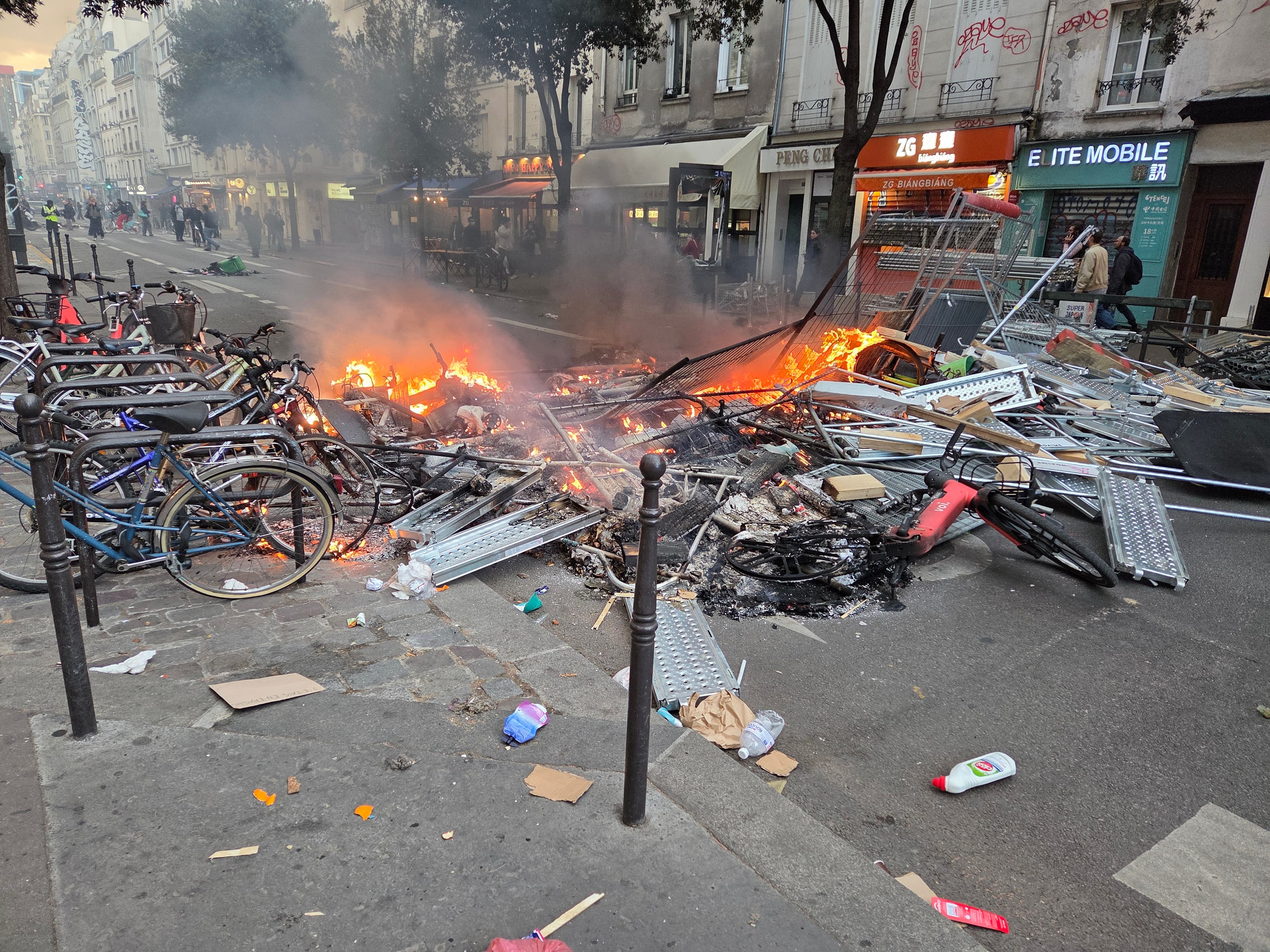 Burning street barricade, damaged bicycles and debris on Rue Beaubourg in Paris on October 17, 2026.